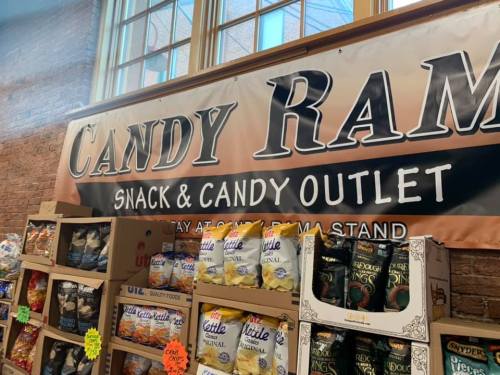 Sign for "Candy Ram" snack and candy outlet, with shelves of snacks and candies in a bright, inviting store.