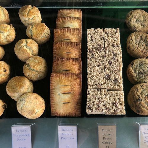 A display of baked goods including scones, pop tarts, and crispy treats, with price tags visible.