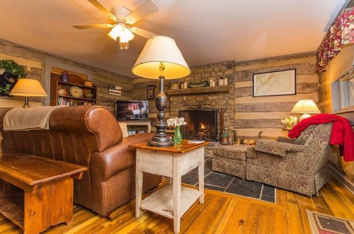 Cozy living room with a stone fireplace, wooden furniture, and warm lighting, creating a welcoming atmosphere.