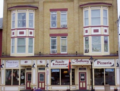 A two-story brick building featuring a family restaurant and pizzeria with large windows and a welcoming entrance.