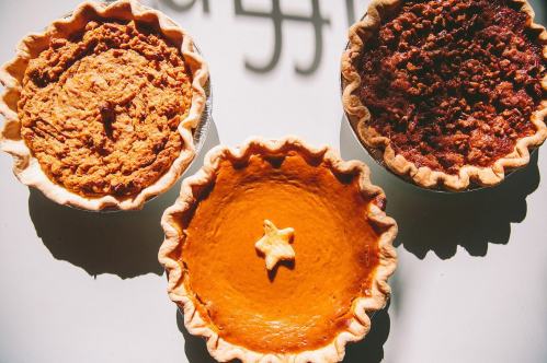 Three pies on a white surface: one pumpkin, one pecan, and one with a star-shaped decoration in the center.