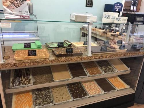 A display case filled with various types of fudge and confections, labeled and arranged on trays.