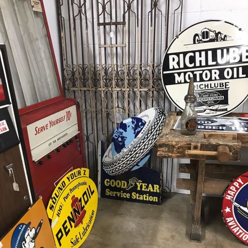 A collection of vintage signs and a gas pump in a nostalgic service station setting.