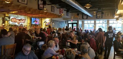 A busy restaurant filled with patrons dining and socializing, with sports memorabilia and a lively atmosphere.