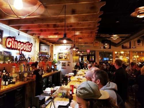 A lively bar scene with patrons enjoying drinks, a bartender serving, and warm lighting creating a cozy atmosphere.