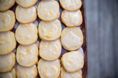 A tray of freshly baked cookies topped with a glossy icing and sprinkled with zest.