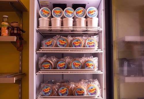 A refrigerator display filled with cups and packages of churros, showcasing a variety of flavors and branding.