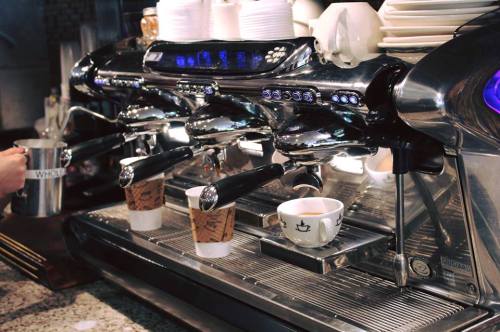 A shiny espresso machine with two coffee cups positioned underneath the spouts, ready for brewing.