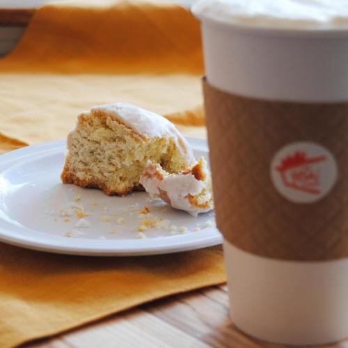 A partially eaten cake on a plate next to a coffee cup, with a yellow cloth in the background.