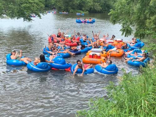 A lively group of people enjoying a summer day floating on colorful inner tubes in a river.