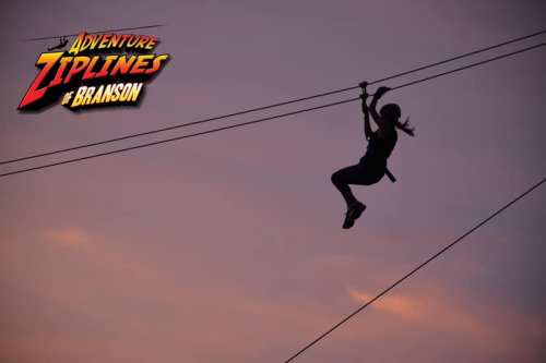 Silhouette of a person ziplining against a colorful sunset sky, with "Adventure Ziplines of Branson" logo in the corner.
