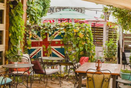 A cozy outdoor café with British flag decor, surrounded by greenery and colorful umbrellas. Tables and chairs are set up.