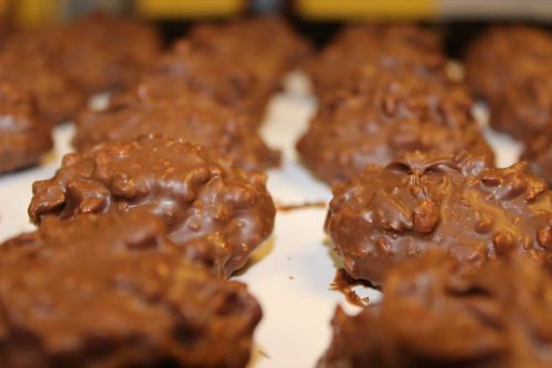 Close-up of chocolate-covered cookies with a textured, crunchy surface, arranged neatly on a white plate.