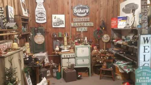 A cozy vintage shop filled with bakery signs, kitchenware, and holiday decor against a wooden backdrop.