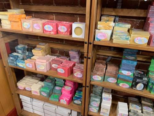 Shelves filled with colorful handmade soaps in various shapes and sizes, neatly arranged with labels.
