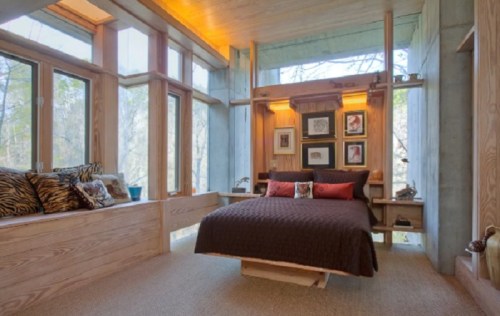 Cozy bedroom with wooden accents, large windows, and a warm color palette, surrounded by nature.