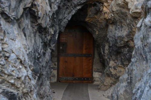 A wooden door set in a rocky cave entrance, surrounded by rough stone walls.