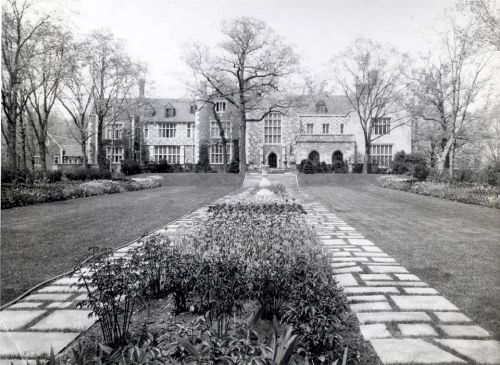 A historic mansion surrounded by manicured gardens and a stone pathway leading to the entrance.