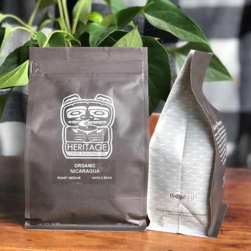 Two bags of coffee on a wooden surface, featuring a logo and text indicating "Organic Nicaragua" and "Medium Roast."