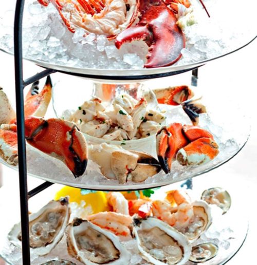 A tiered seafood platter featuring lobster, crab, shrimp, and oysters on ice.