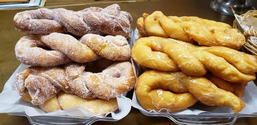 Two trays of twisted pastries: one coated in sugar and the other glazed, showcasing a golden-brown color.