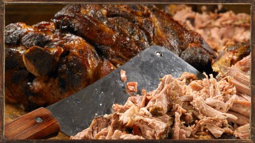 A close-up of shredded meat with a cleaver, alongside a larger piece of roasted meat in the background.