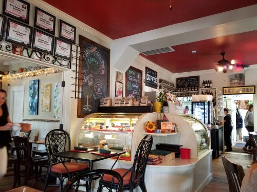 Cozy café interior with chalkboard menus, a display case, and wooden tables, featuring warm lighting and decorative elements.