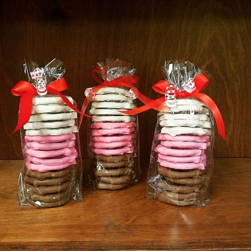 Three stacked cookie gift bags tied with red ribbons, featuring layers of chocolate, pink, and white cookies.