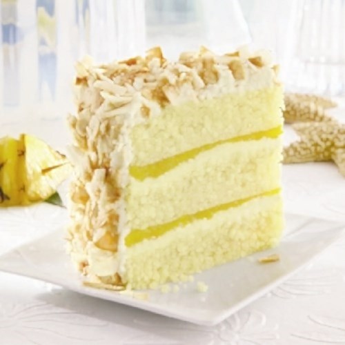 A slice of layered cake with yellow filling, topped with coconut flakes and almonds, on a white plate.