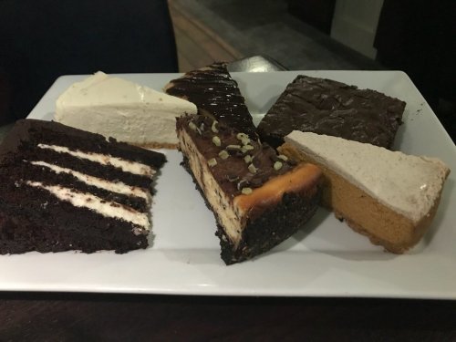 A platter of assorted desserts including chocolate cake, cheesecake, and pumpkin pie slices.
