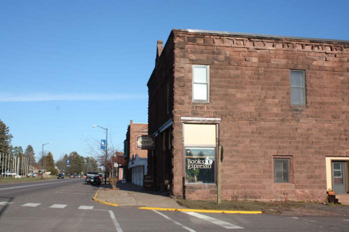 A corner building with a bookstore and espresso shop sign, set on a quiet street under a clear blue sky.