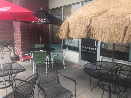 Outdoor seating area with tables and chairs, featuring umbrellas and a thatched roof, outside a restaurant.