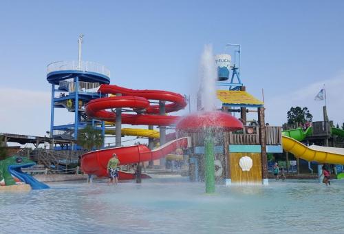 Colorful water slides and a splash pad at a water park, with people enjoying the attractions on a sunny day.