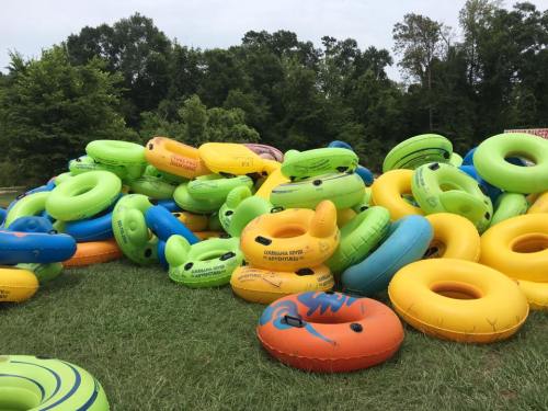 A colorful pile of inflatable tubes in various sizes and designs, set against a green grassy background.