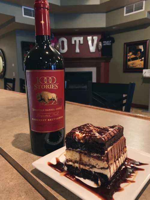 A bottle of 1000 Stories bourbon barrel-aged Cabernet Sauvignon next to a chocolate dessert drizzled with sauce.
