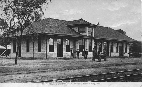 Historic black-and-white photo of a train station in Fort Valley, Georgia, with people and a cart in front.