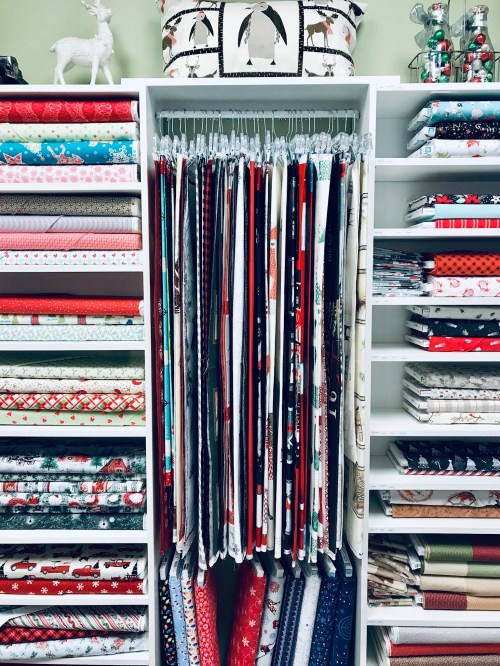 A neatly organized display of colorful holiday wrapping paper in various patterns, hanging on a rack.