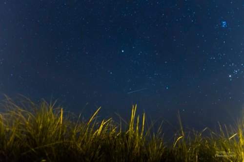 A starry night sky with a few visible stars and a hint of grass in the foreground.