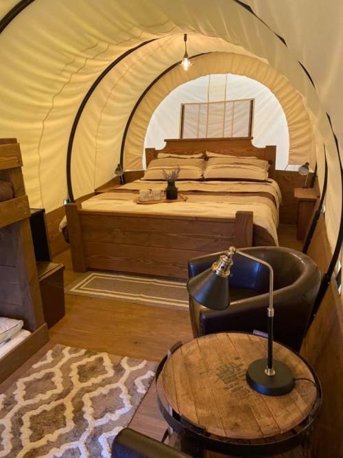 Cozy interior of a glamping tent featuring a wooden bed, seating area, and warm lighting.