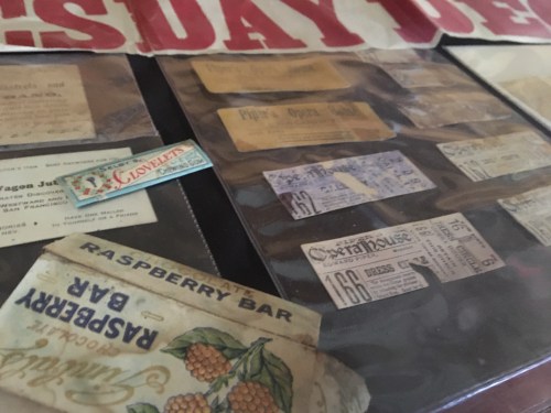 A collection of vintage tickets and advertisements displayed under glass, including "Raspberry Bar" and "Phil's Opera."