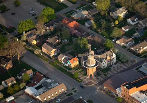 Aerial view of a neighborhood featuring houses, trees, and a windmill at the intersection of two streets.