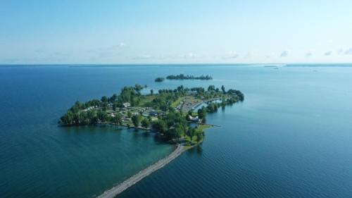 Aerial view of a serene island surrounded by calm blue waters, featuring lush greenery and a sandy shoreline.