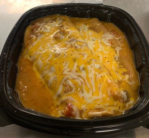 A black takeout container filled with cheesy enchiladas topped with melted cheese and sauce.