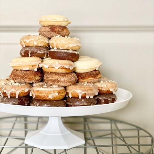 A tiered display of assorted donuts, featuring various glazes and toppings, arranged on a white cake stand.