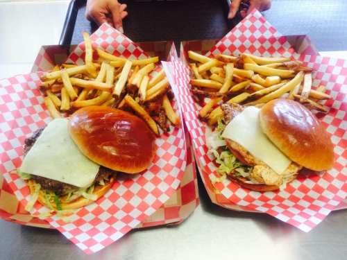 Two trays with burgers topped with cheese and lettuce, accompanied by a generous serving of French fries.