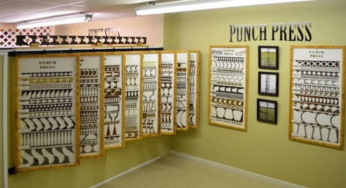 A room displaying various punch press patterns on boards, with framed images on the wall.
