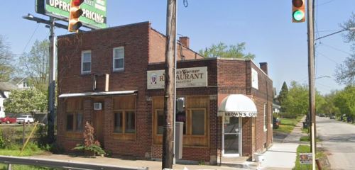 A brick building with a restaurant sign and an awning, located at a street corner with traffic lights.