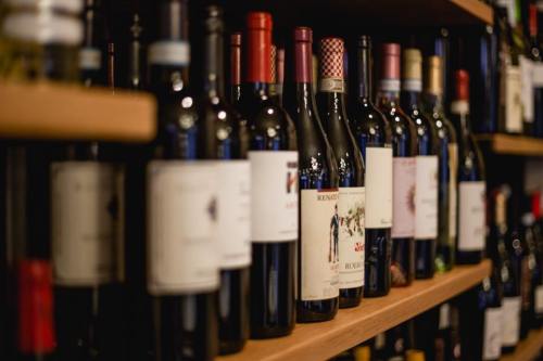 A close-up of a wooden shelf filled with various wine bottles, showcasing different labels and colors.