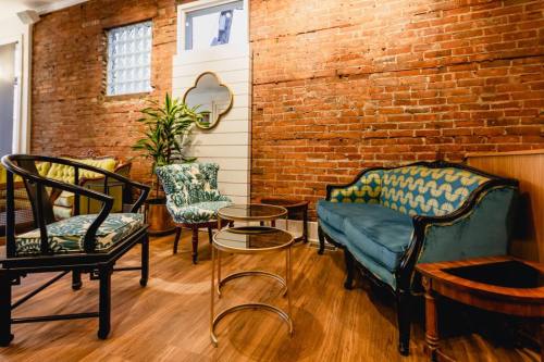 Cozy interior featuring a mix of vintage furniture, including a blue sofa, patterned chairs, and wooden tables against a brick wall.