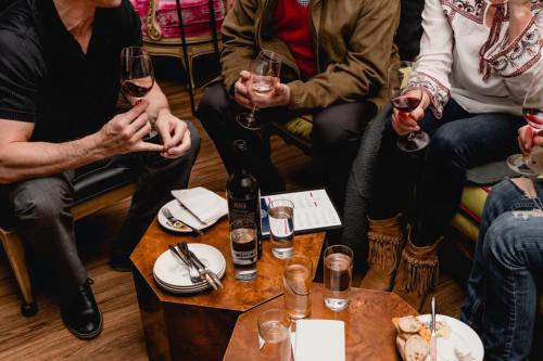 A group of people holding wine glasses around a table with food and drinks in a cozy setting.